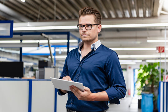 Businessman with tablet in production hall portrait