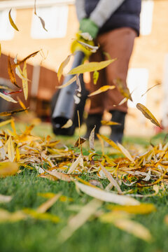 Man using leaf blower in autumn garden wearing casual clothing