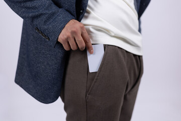 Close up of man putting card or phone into pocket.