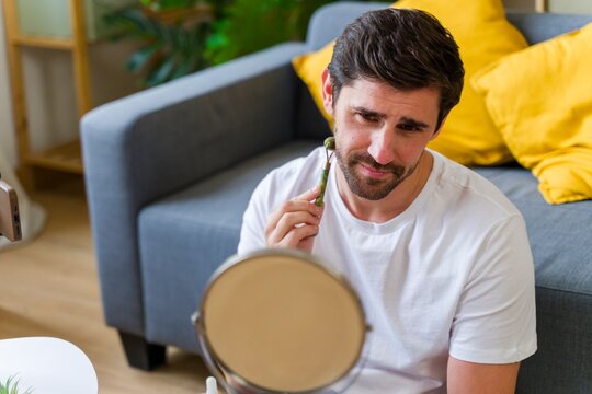 Man practicing mindfulness with jade roller at home in living room