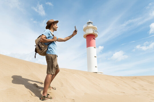 Tourist exploring sand dunes with lighthouse at Delta del Ebre Spain
