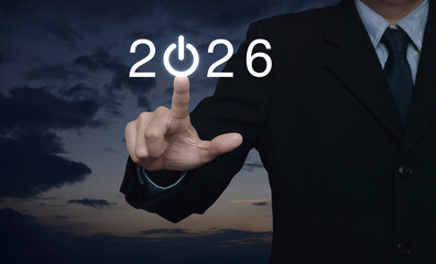 Businessman pressing 2026 start up business flat icon over sunset sky, Business happy new year 2026 success concept