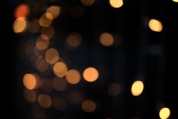 Warm golden bokeh lights illuminating dark abstract background with copy space