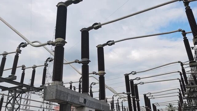 Panning view of high voltage electrical substation switchyard with insulators and busbars.