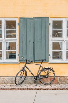 Classic Black Bicycle Against Yellow Facade and Green Shutters of Nyboder District, Historic Naval Barracks, Copenhagen, Denmark