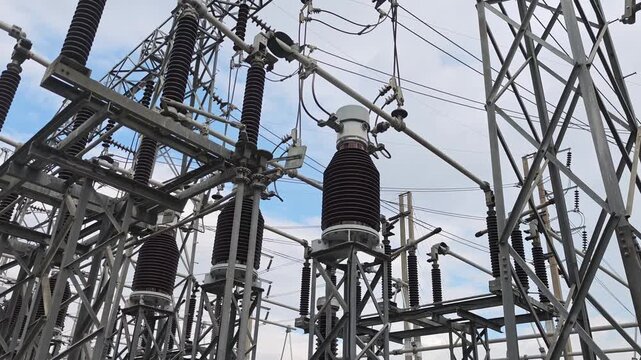 Panning view of high voltage electrical substation switchyard with insulators and busbars.