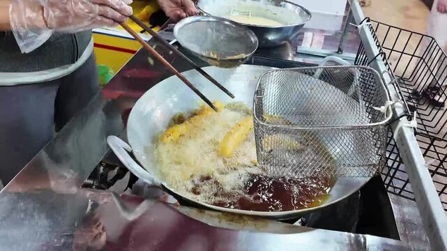 Street Food Vendor Skimming Oil While Frying Banana Dessert at Night Market in Da Nang, Vietnam