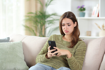 Disappointed woman in green checking boring phone content
