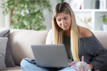 Shocked woman checking strange content on laptop