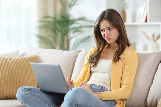 Suspicious woman in yellow checking laptop in a house