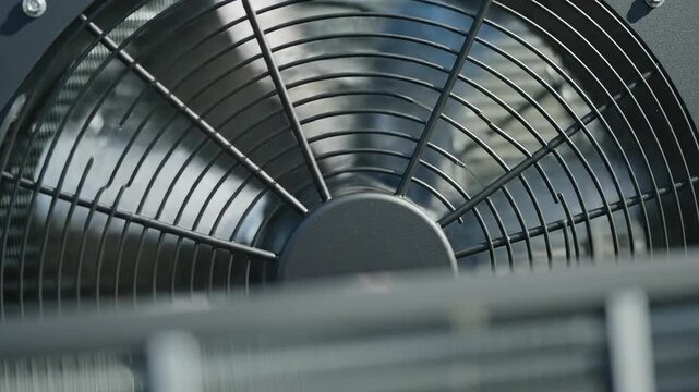 Extreme close-up slow motion shot of a modern air source heat pump condenser fan spinning rapidly for residential climate control sustainable, appliance, engineering