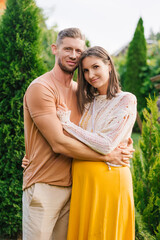 Smiling Couple Expecting Child Hug In Garden