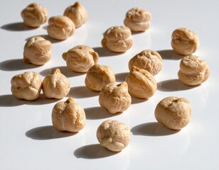 Scattered light-tan chickpeas with subtle textures against a bright white surface