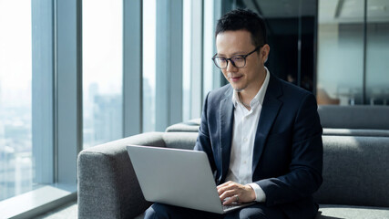 Asian businessman working on laptop during corporate meeting