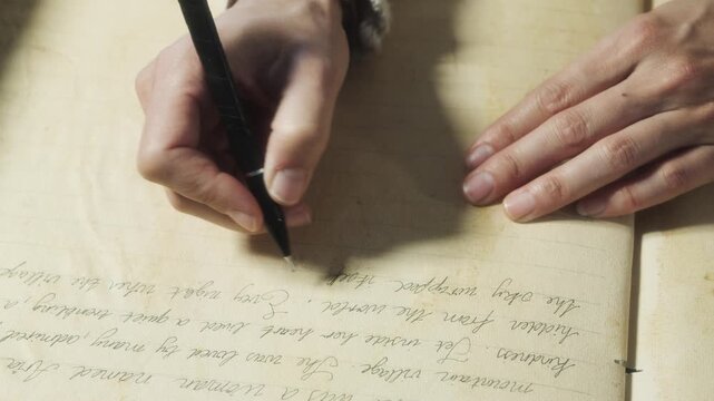 Close-up of hands writing in an old notebook under warm natural light.