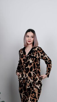 Woman in leopard print pajamas posing on white background.