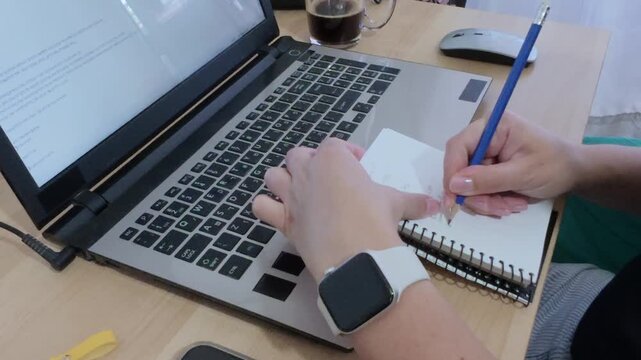 Writer drafting ideas in a notebook before typing on a laptop.