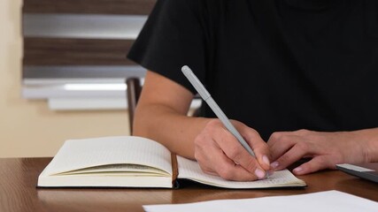 Hand writing in a planner during a business meeting.