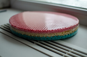 These are pre-packaged colorful waffle cake layers ready-made sponge sheets for assembling a layered cake, featuring a vibrant gradient of pink, beige, and turquoise, with a classic waffle texture, 