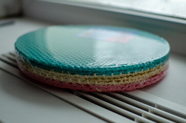 These are pre-packaged colorful waffle cake layers ready-made sponge sheets for assembling a layered cake, featuring a vibrant gradient of pink, beige, and turquoise, with a classic waffle texture, 