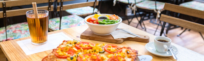 Banner of restaurant table with vegetarian focaccia, colorful salmon and edamame poke bowl, iced tea and espresso on wood, inviting casual lunch with fresh choices. Organic fast food concept.