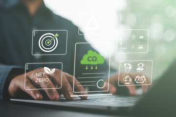 Close-up of person using a laptop with net zero and carbon reduction icons, symbolizing CO₂ reduction, recycling, green energy, and sustainable digital innovation.