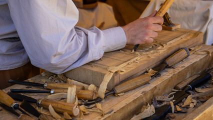 A person carving wood with various tools.