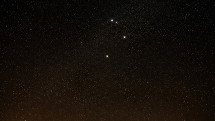 A starry night sky displays a multitude of white and yellow stars in the vast celestial landscape viewed from a distant location.