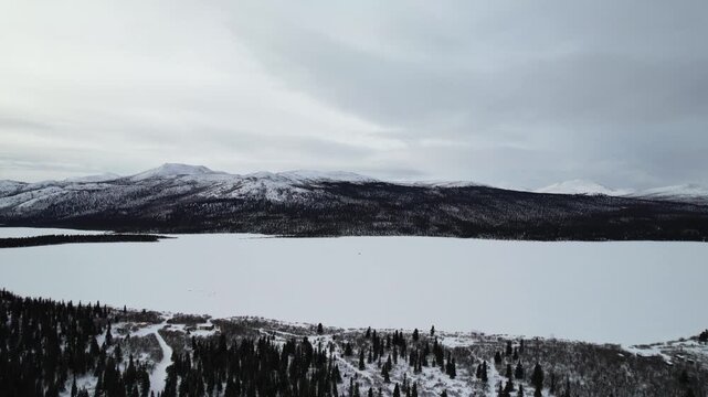 An aerial view captures the vast, snow-covered landscape and frozen surface of Fish Lake (Łu Zil M&auml;n), located near Whitehorse, Yukon, Canada. This area, significant to the Kwanlin D&uuml;n First Nation
