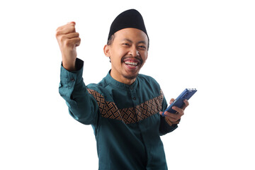 Joyful young Asian Muslim man in a green patterned koko shirt and black peci (songkok), smiling and...