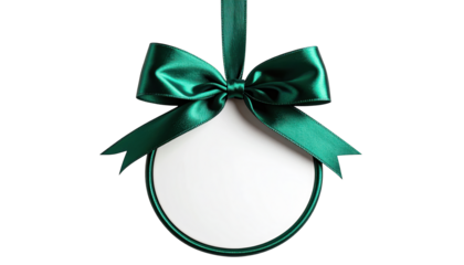 Green satin bow holds white circular ornament, hanging against black backdrop