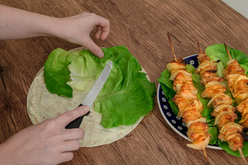 Preparing party snacks: grilled turkey skewers, tortilla and salad