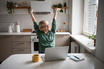 Satisfied middle aged businesswoman warming up body after successfully finishing work tasks and...
