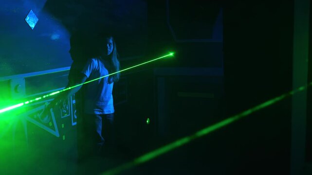 Children pass an obstacle course with lasers and sensors. A room with green lasers and obstacles, an exciting active obstacle course game. Laser tag.