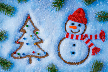 Top view of snowy holiday figures decorated with colorful baubles, a red hat, and a striped scarf. Festive winter composition on a blue background.