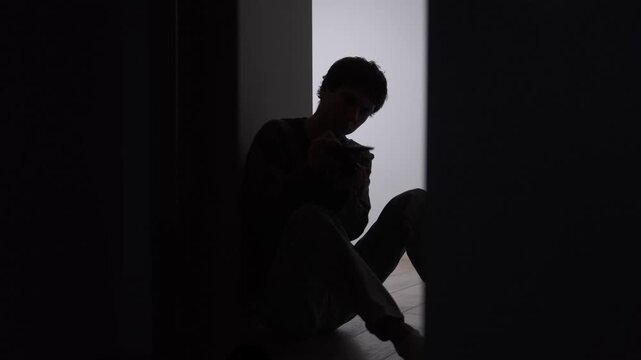 Man counting coins from wallet, low income financial stress, lonely silhouette sitting on floor in dark corridor, lack of money, poverty concept and personal finance hardship