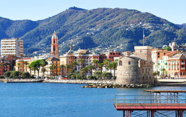 Panoramic view of traditional buildings and structures of Liguria. Mountains of Italy. Mediterranean nature, Europe. Sky, sea, and palm trees of Rapallo. Design backdrop. Tourism and recreation.