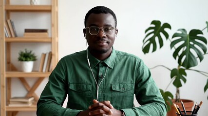 Young professional on virtual video call from home office, wearing glasses and earphones, representing remote work and digital communication - Powered by Adobe