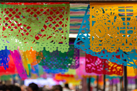 Close-up shot of colorful Papel Picado banners hanging as decorations for a traditional Mexican celebration.