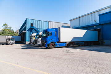 Trucks parked at a modern logistics warehouse, loading and unloading goods for transport and supply chain operations