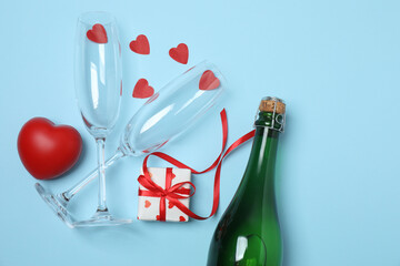 Festive background with a bottle of champagne, two glasses and hearts and gift boxes. A romantic...