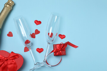 Festive background with a bottle of champagne, two glasses and hearts and gift boxes. A romantic...