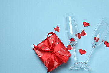 Festive background with a bottle of champagne, two glasses and hearts and gift boxes. A romantic...