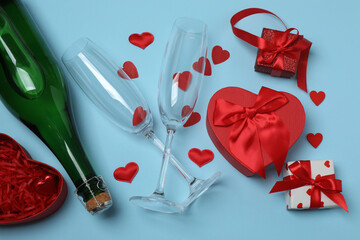 Festive background with a bottle of champagne, two glasses and hearts and gift boxes. A romantic...