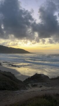 Dramatic cloudy sunset over ocean waves and sandy beach with moody skyx