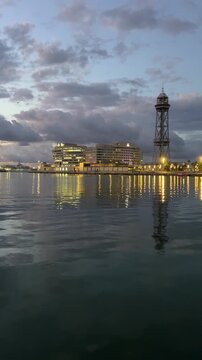 Barcelona harbor at dusk with city lights and reflections on calm water