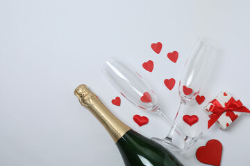 Festive background with a bottle of champagne, two glasses and hearts and gift boxes. A romantic...
