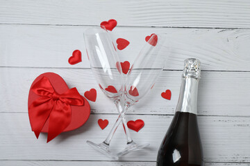 Festive background with a bottle of champagne, two glasses and hearts and gift boxes. A romantic...