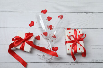 Festive background with a bottle of champagne, two glasses and hearts and gift boxes. A romantic...