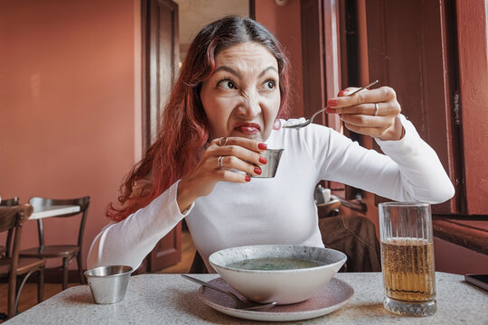 Woman reacting with disgust to bad food while eating in a restaurant. Unpleasant experience with meal